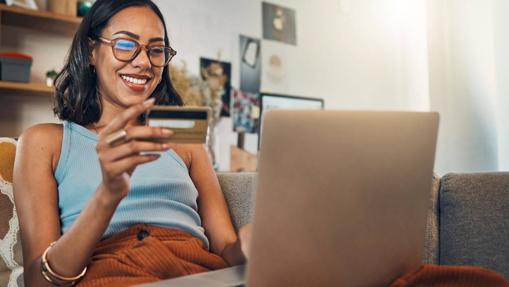 Smiling female making payment on laptop with bank card