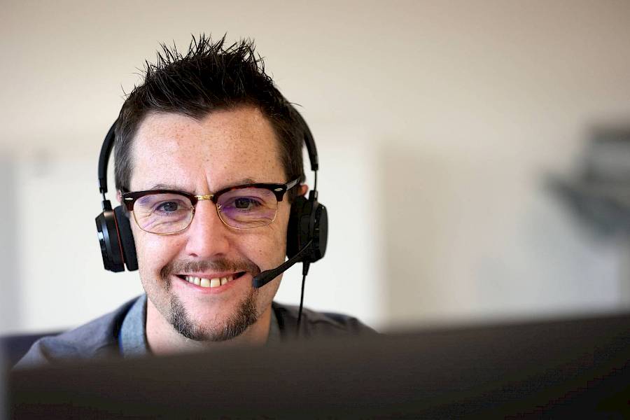 Male customer service agent wearing headset and smiling