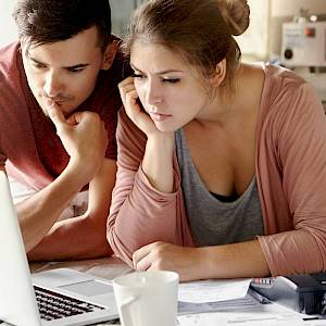 Young couple with bills staring at laptop