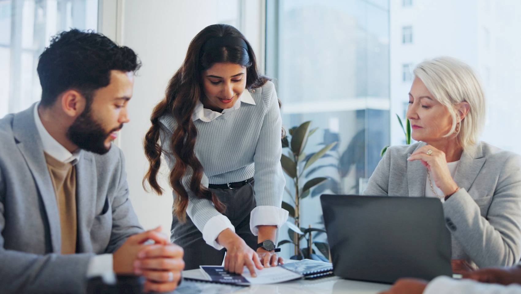 professional male and female team looking at laptop screen smiling in office setting