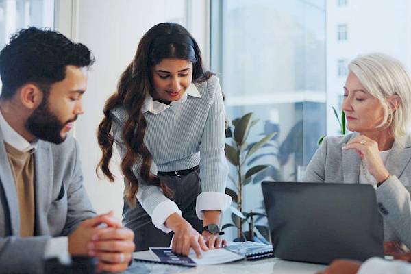 professional male and female team looking at laptop screen smiling in office setting